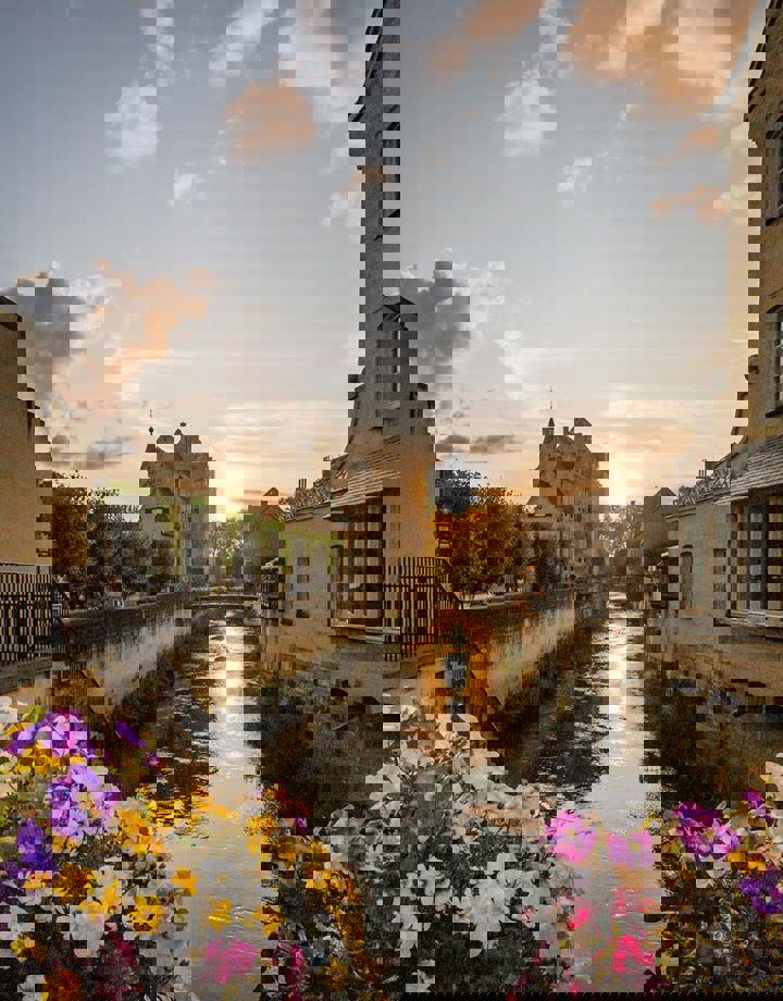 Beeld van Valkenburg met ondergaande zon vanaf met bloemen versierde brug richting Geulpoort