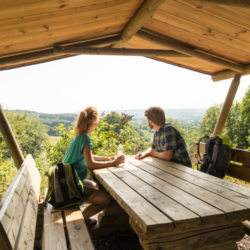 Twee wandelaars zittende op een overdekte picknickplek op het Drielandenpunt