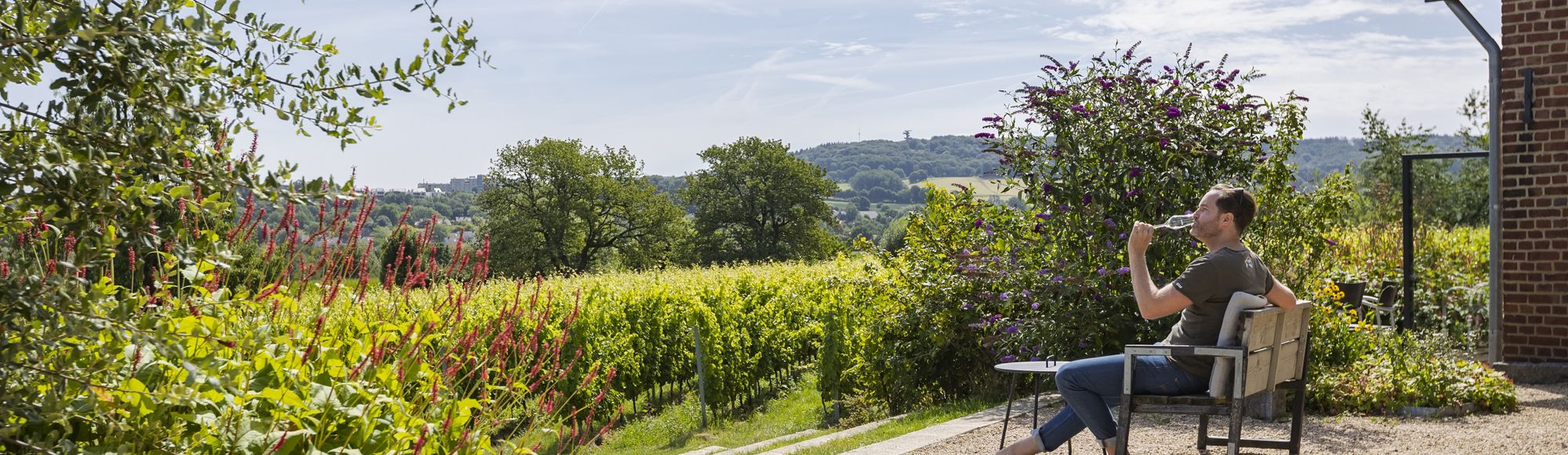 Genieten van een glaasje mousserende wijn op het terras van Domein Holset met uitzicht op de wijngaarden